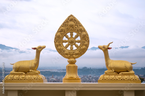 Bouddha, Nepal. Buddhist symbol of the Dharma Chakra flanked by two deer and Bouddha stupa in the background. photo