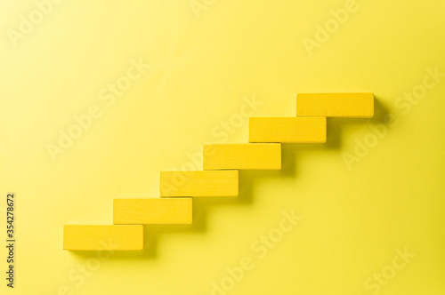 Concept of building success foundation. Yellow wooden block stacking as step stair, Success in business growth concept on black background.