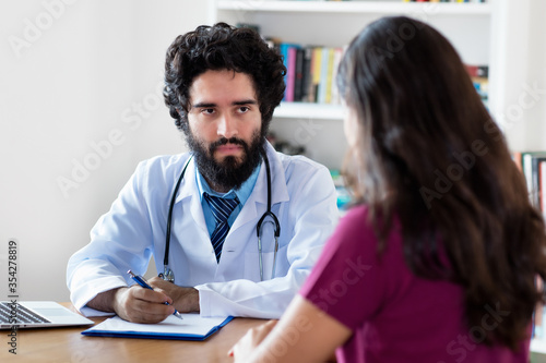 Pakistani male doctor talking to female patient
