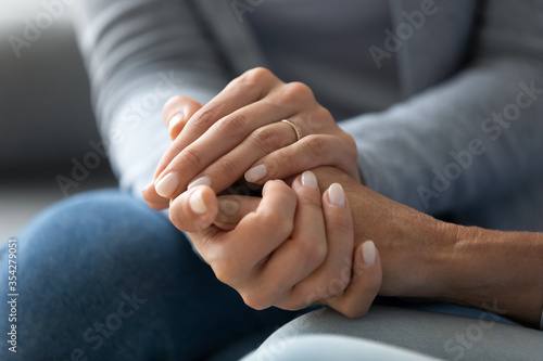 Close up caring grown up daughter holds mother hand provides psychological support  touch arms symbol of asking of forgiveness  heart-to-heart talk with reliable person  empathy and compassion concept