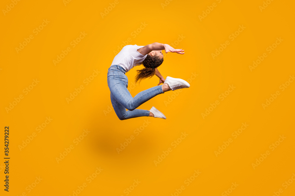 Full size profile photo of amazing lady flexible body bending spine artist dancer performance jumping high wear white t-shirt jeans isolated yellow bright color background - obrazy, fototapety, plakaty 
