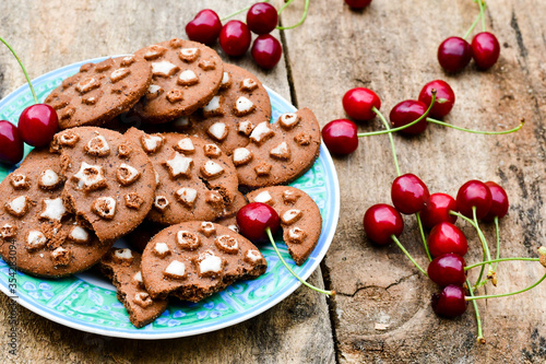    Fresh organic Cherryes and cocoa cookies with  vanilla star decoration on wooden background. Summer dessert photo