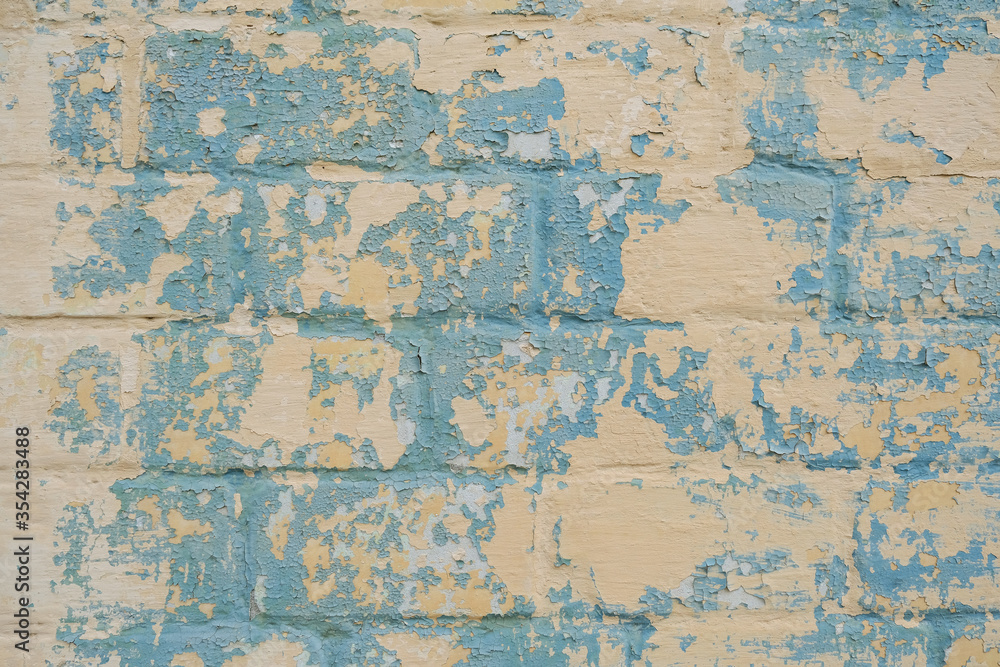 Blue Old colorful paint with cracks on yellow brick wall