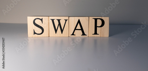 The word swap was written with wooden cubes. Close-up of spot lights and on a white table. Close up.