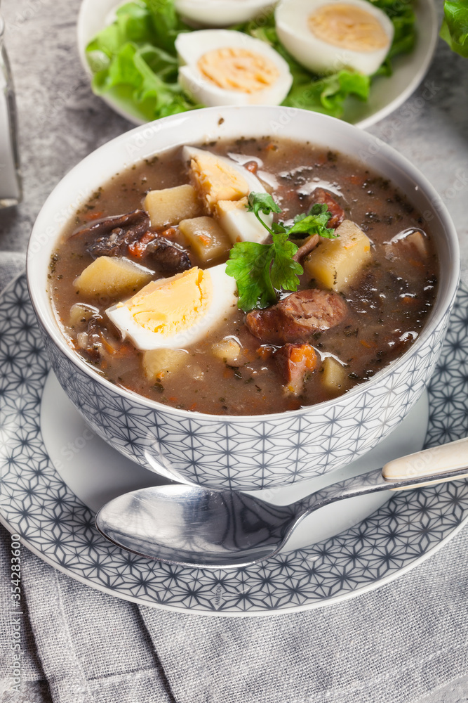 The sour soup made of rye flour with mushrooms served with eggs