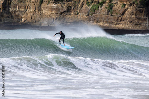 Japan surfing , sometimes during a typhoon, there are many waves in Japan especially in Hebara, Katsuura, Chiba. Westerner surfs large waves. Sunrise & at the beach with a surfer & his surf board. photo