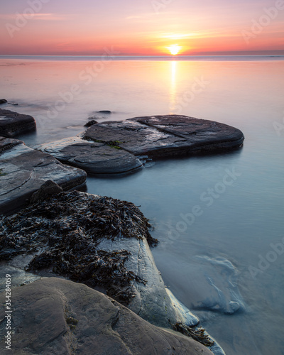 View at sunrise at Old Hartley Bay on the north east coast of England, looking out to sea and towards St Marys Lighthouse at Whitley Bay.