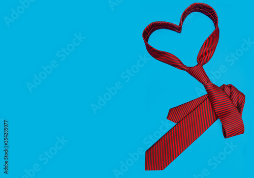father's day. red heart-shaped tie and space for text on a blue, blue background.