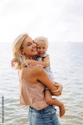 Happy mom on vacation hugs her little laughing son