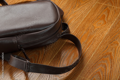Backpack made of brown genuine leather on a wooden background.