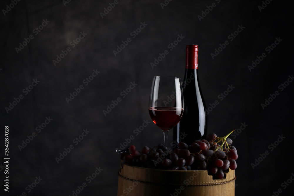 The red wine in the glass, along with a bottle of wine made from red grapes, is laid on a wooden floor and a beautiful backdrop. Ready for partying