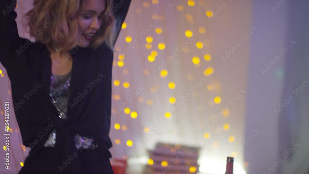 Slowmo tilt down of beautiful young female DJ smiling and dancing while playing music at house party Slowmo tilt down of beautiful young female DJ smiling and dancing while playing music at house party