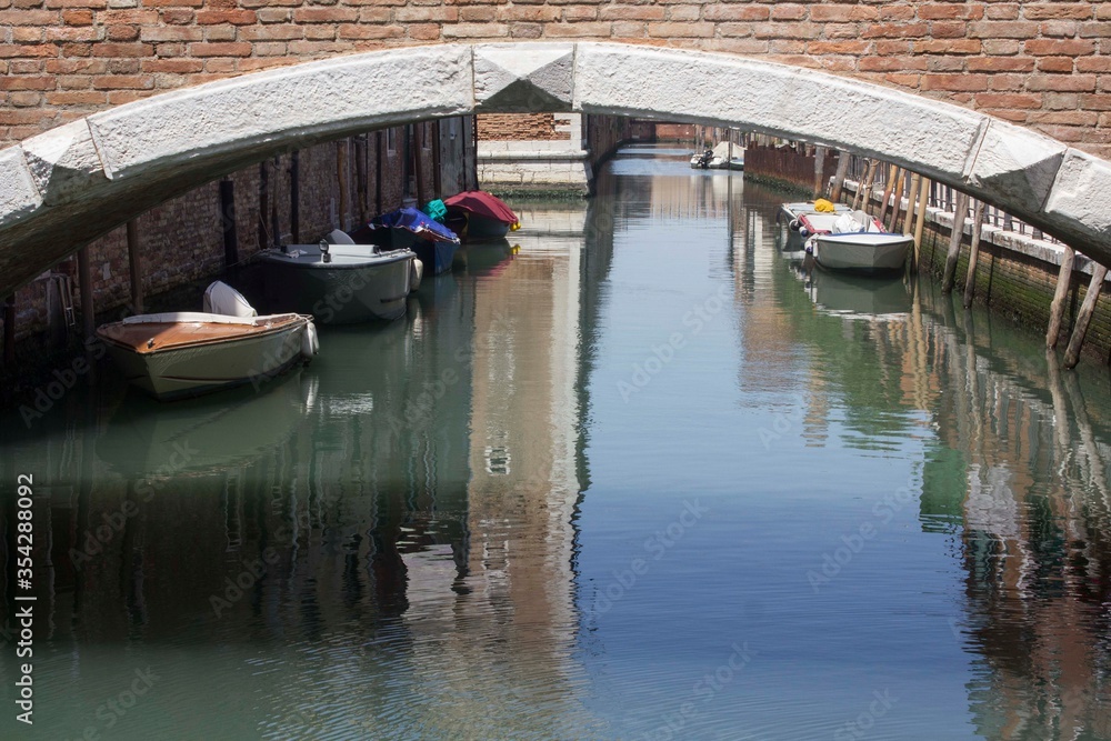 Anchored boats under a bridge in venice in Arsenal disctrict, Italy