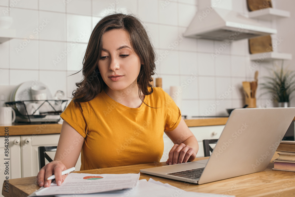 attractive freelancer looking at charts and graphs near laptop attractive freelancer looking at charts and graphs near laptop