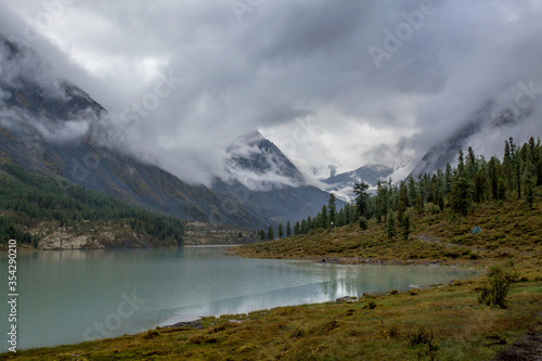 Akkem Lake at the foot of Belukha Mountain in Altai. Reflection of the mountain in the water. Low cloud cover.
