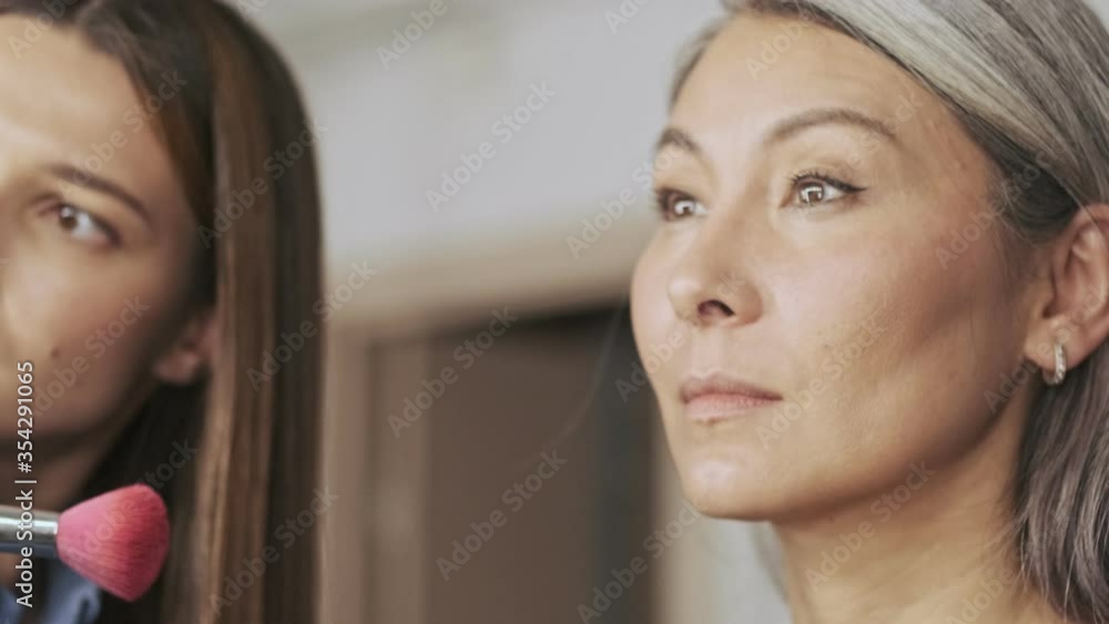 A close-up view of a gorgeous elderly woman client with a pretty nice makeup artist in a beauty salon A close-up view of a gorgeous elderly woman client with a pretty nice makeup artist in a beauty salon