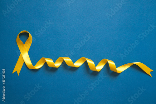 Yellow ribbon on the blue dimple background. Childhood cancer awareness concept. Cancer concept.  