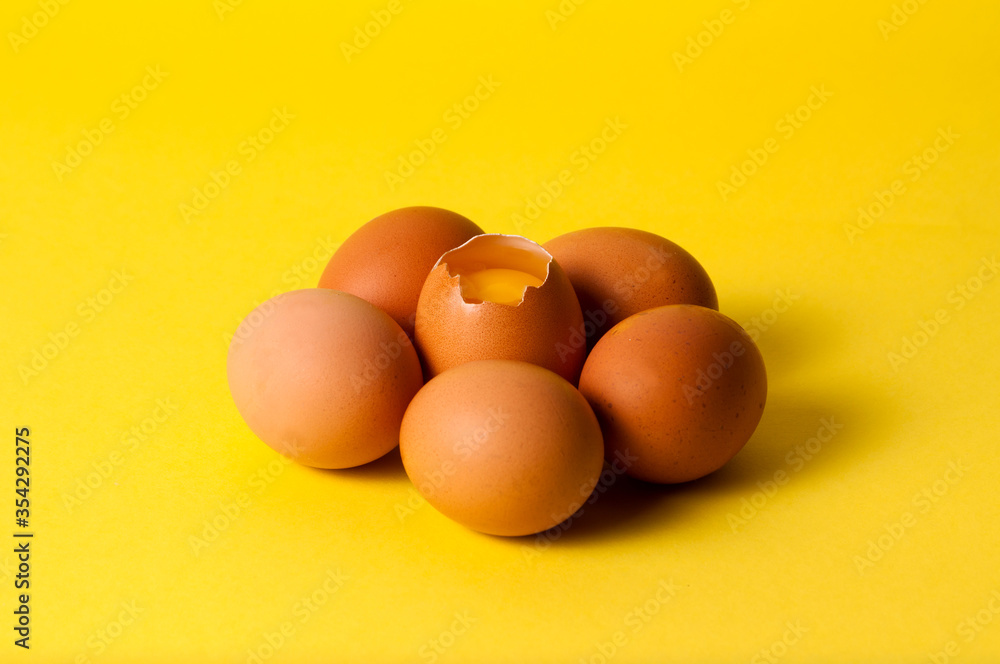Brown eggs on a yellow background, visible yolk