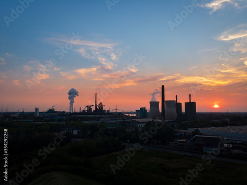 Scenic view of industrial landscape power station and cooling tower at sunset against sky.
