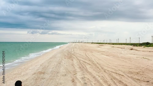 young pair or couple of lovers hold hands and walk along the sand of a coastline beach