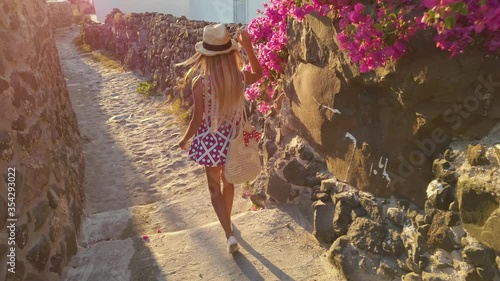 Greece, young stylish woman or fashionable girl walks along a street in resort town in greek resort