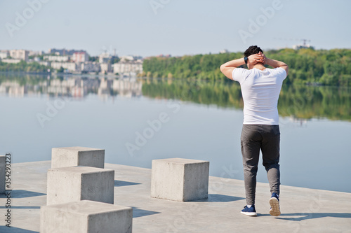 Portrait sports arabian man in black medical face mask doing morning workout exercises against lake during coronavirus quarantine. © AS Photo Family