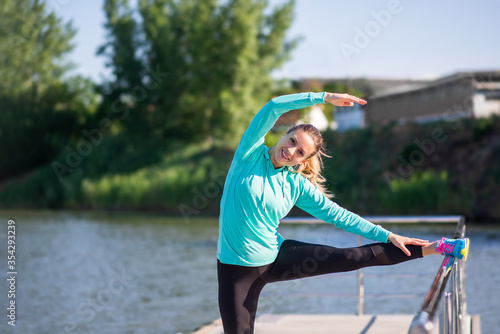 Beautiful happy smiling young woman stretching leg while warming up © eshana_blue