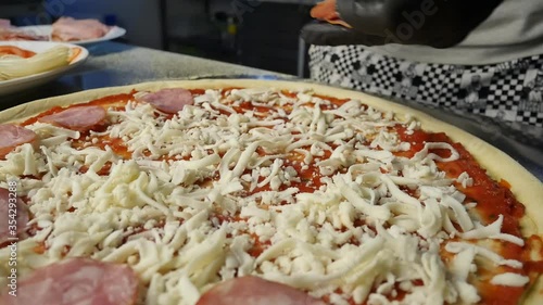 closeup of dressing pizza cheese at italian restaurant