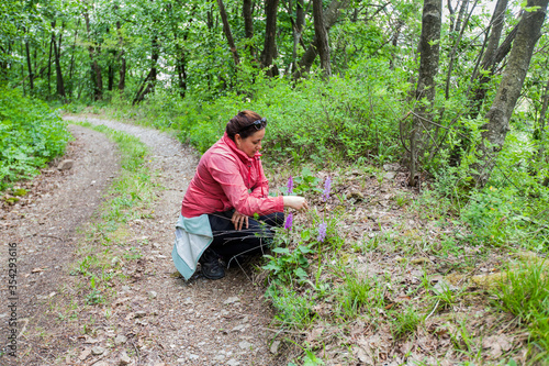Woman hiker enjoy wildflowers in the forest on spring day in nature.