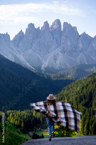 girl in hat and poncho is walking in dolomites