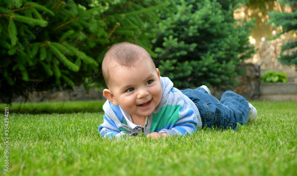 Happy toddler boy playing on green grass. Smiling baby boy Happy toddler boy playing on green grass. Smiling baby boy