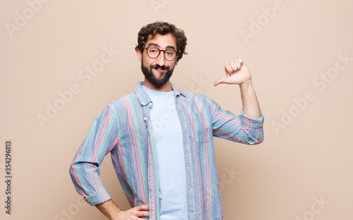 young bearded man against flat wall