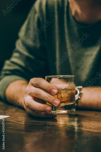 guy drinks whiskey with ice at the bar