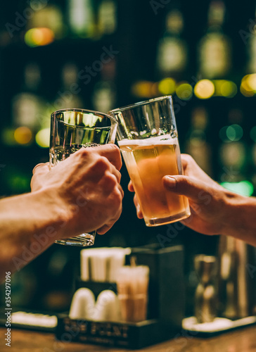 Photography two men clink glasses of beer at a bar