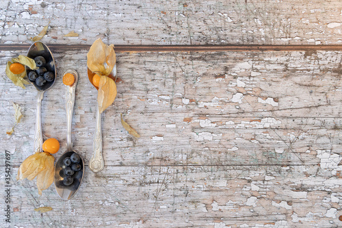 three teaspoons shot from above with physalis and blueberries, shot on a textured wooden background