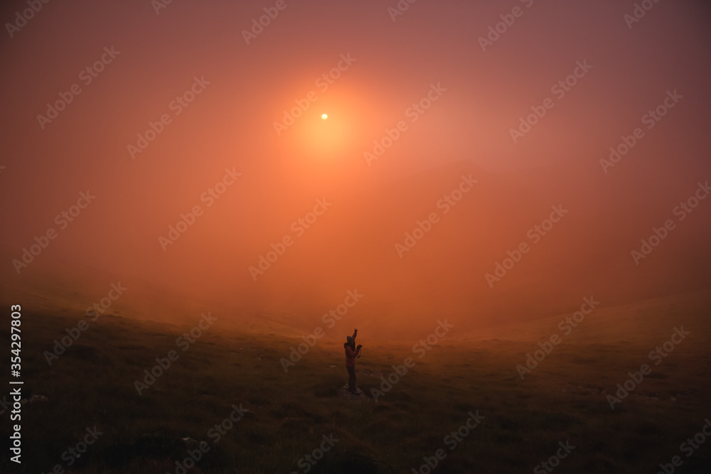 girl photographs the sunset in the mountains