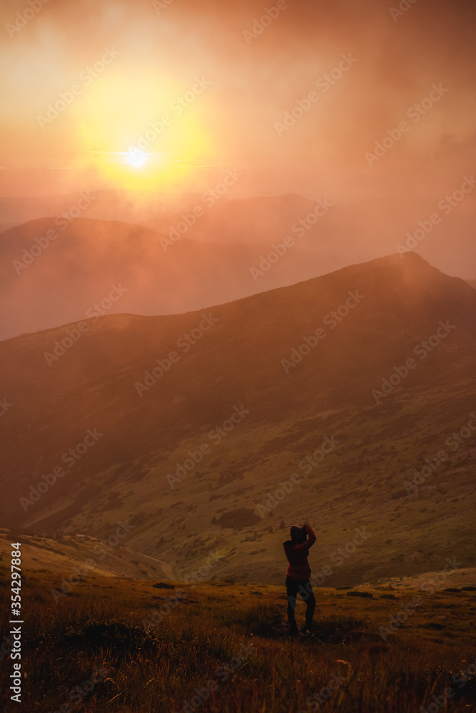 girl photographs the sunset in the mountains