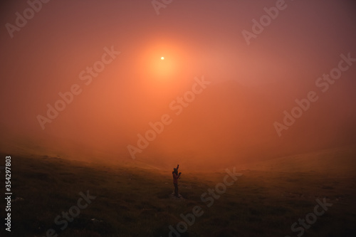 girl photographs the sunset in the mountains © Andrey