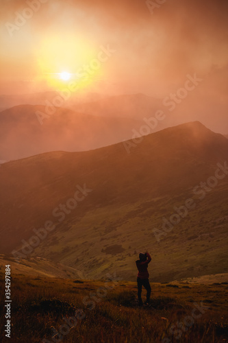 girl photographs the sunset in the mountains