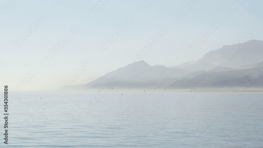 Foggy morning by the sea, birds flying, mountains background by the Red sea, Ain Sokhna Egypt, peaceful inspirational mood