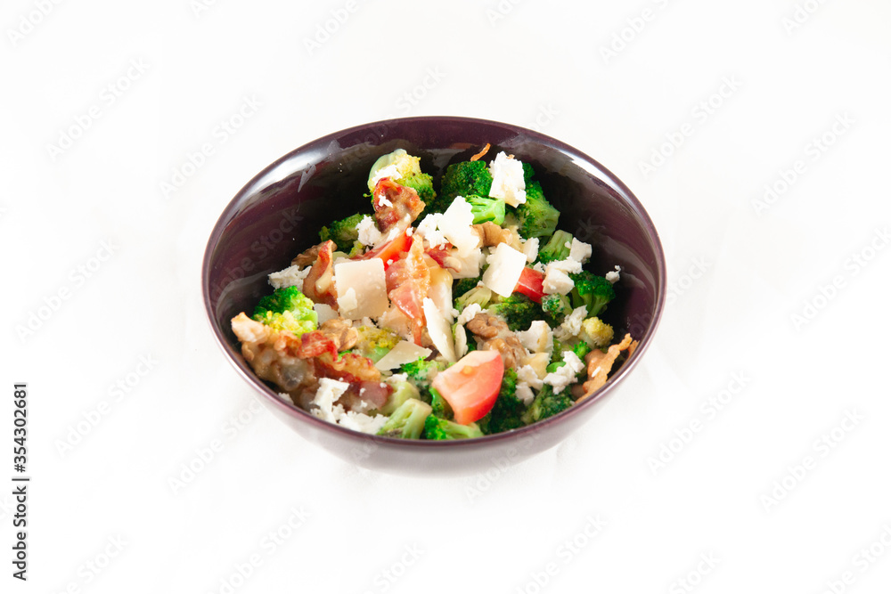 Broccoli Salad with Bacon, parmesan cheese in a black plate. Isolated on white.