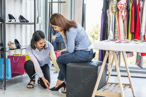 Young Asian woman sale person showing shoe for a customer to try on.
