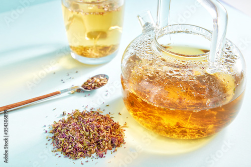 Thyme antiviral drink in a glass kettle. Thyme organic drink in a glass cup on colored background