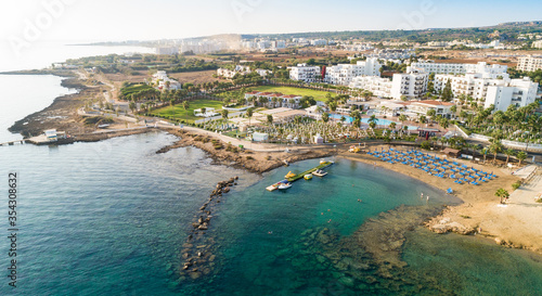Aerial bird's eye view of Pernera beach in Protaras, Paralimni, Famagusta, Cyprus. Tourist attraction golden sandy bay with sunbeds, water sports, hotels, restaurant, people swimming in sea from above © f8grapher