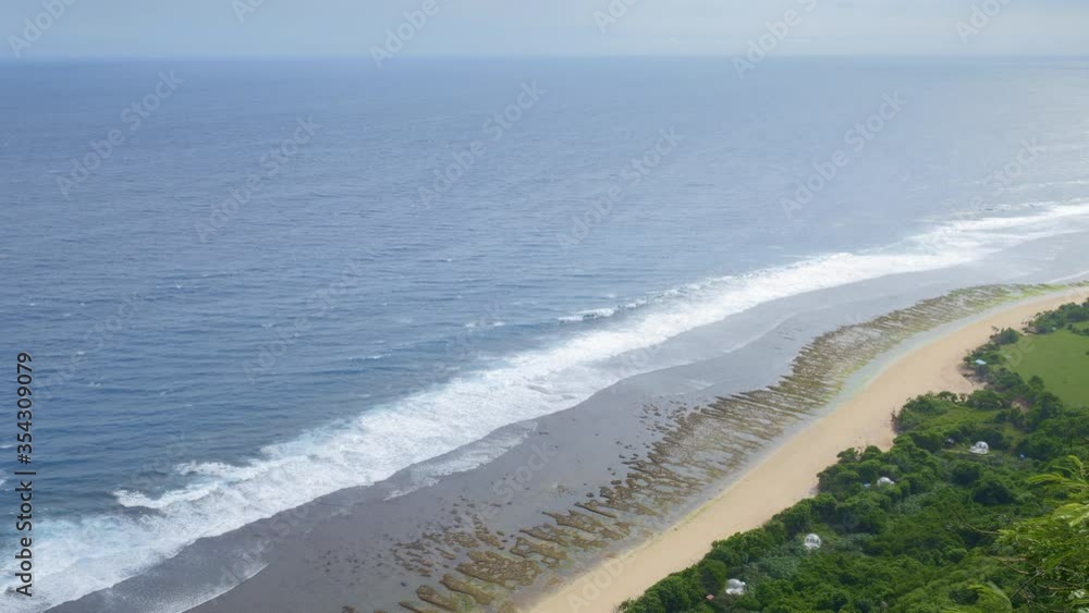 View from top of a beach with green trees and grass during low tide View from top of a beach with green trees and grass during low tide