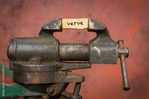 Fotografie Vice grip tool squeezing a plank with the word verve