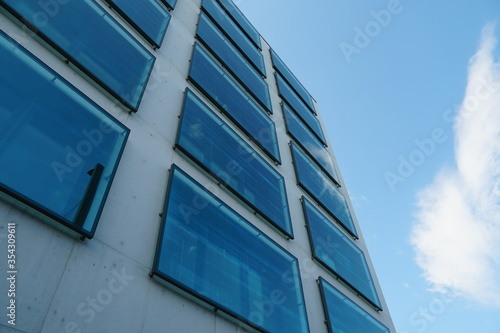a facade of a modern corporate building with large square window in upward perspective