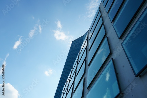 a facade of a modern corporate building with large square window in upward perspective with sky on the background