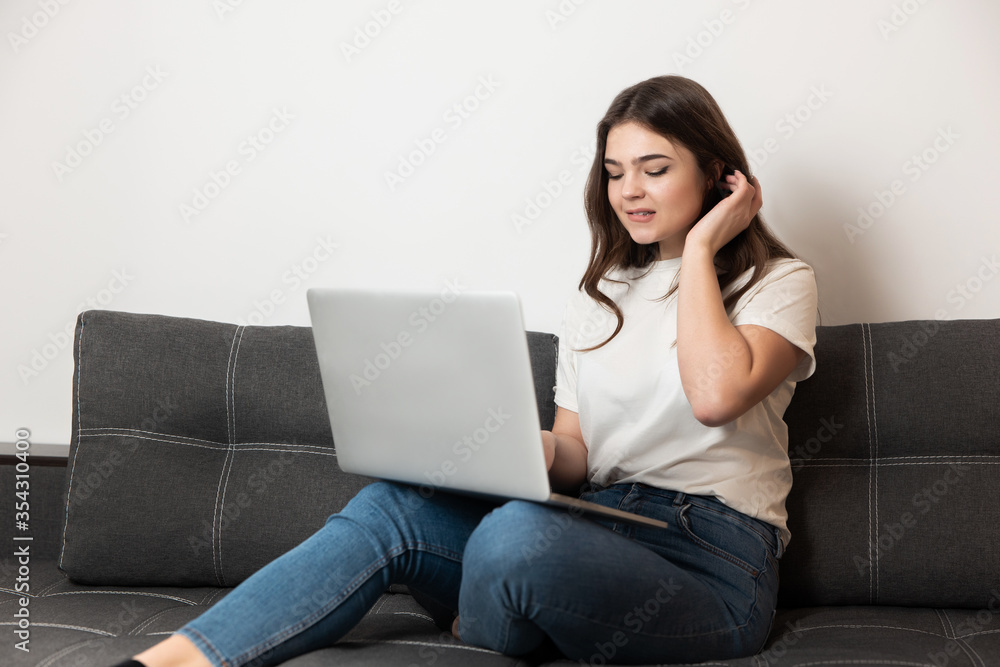 young beautiful brunette woman working from home in her laptop sitting on the sofa in her appartment during quarantine isolation, stay safe home concept young beautiful brunette woman working from home in her laptop sitting on the sofa in her appartment during quarantine isolation, stay safe home concept