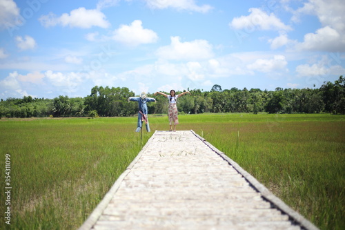 A woman standing on a wooden bridge in a rice field